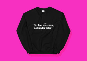 Black jumper reads in white "Six feet over now, not under later" with daggers pointing right and down, respectively. Sans serif font.